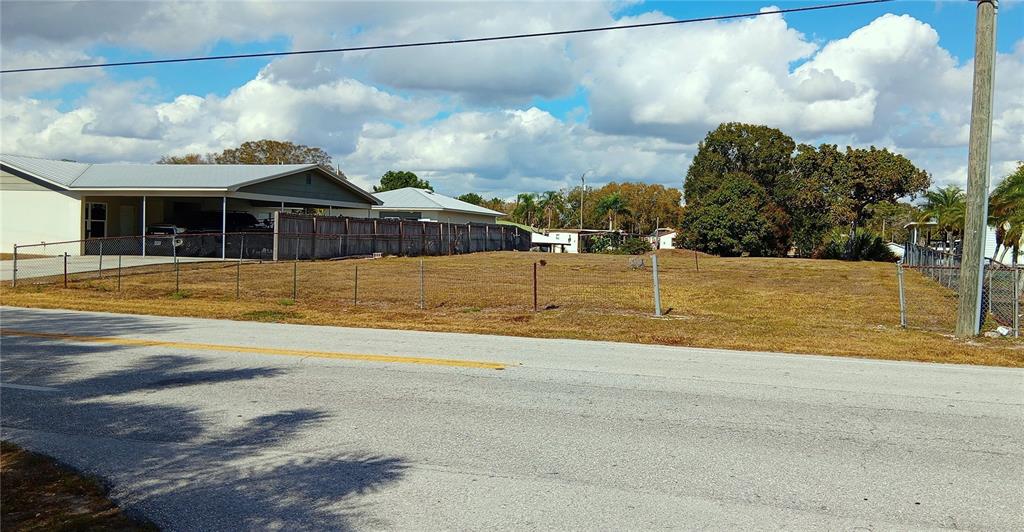 A vacant, fenced-in grassy lot sits next to a house with a carport — 3431 SE 28TH STREET, OKEECHOBEE, FL