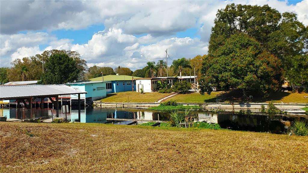 A canal flows in front of a residential property with a boat dock and houses — 3431 SE 28TH STREET, OKEECHOBEE, FL