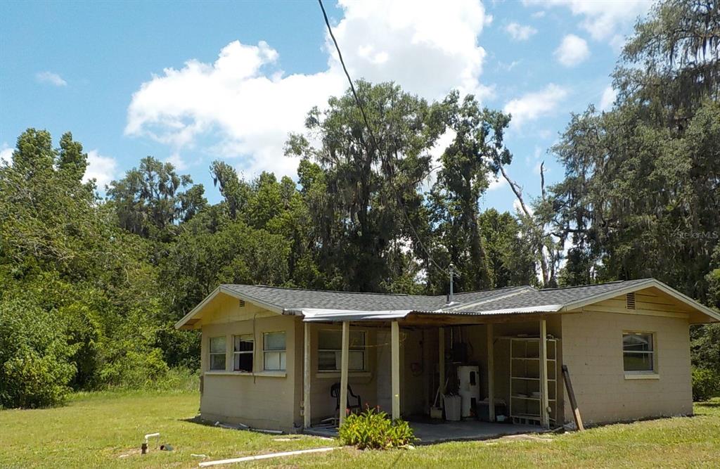 A single-story house with a tan exterior and a covered patio sits on a grassy lot — 6404 SW 9TH AVENUE, OCALA, FL