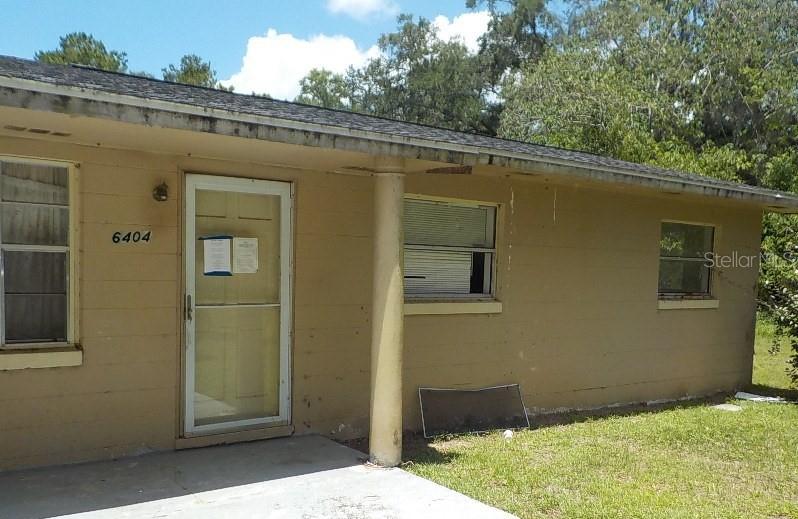 A single-story house with tan exterior walls, a concrete porch, and a white front door — 6404 SW 9TH AVENUE, OCALA, FL