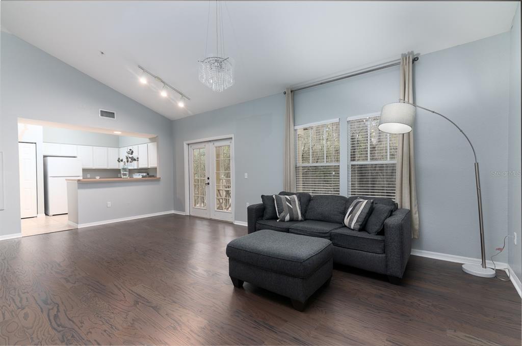 A dining area with wood floors opens to a kitchen and a balcony with outdoor seating — 4850 SW 91ST TERRACE UNIT 301, GAINESVILLE, FL