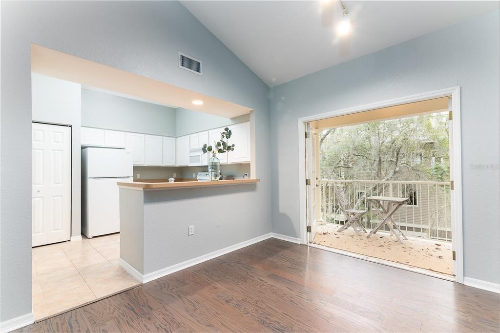 A spacious living room with high ceilings, hardwood floors, and an adjacent kitchen area — 4850 SW 91ST TERRACE UNIT 301, GAINESVILLE, FL