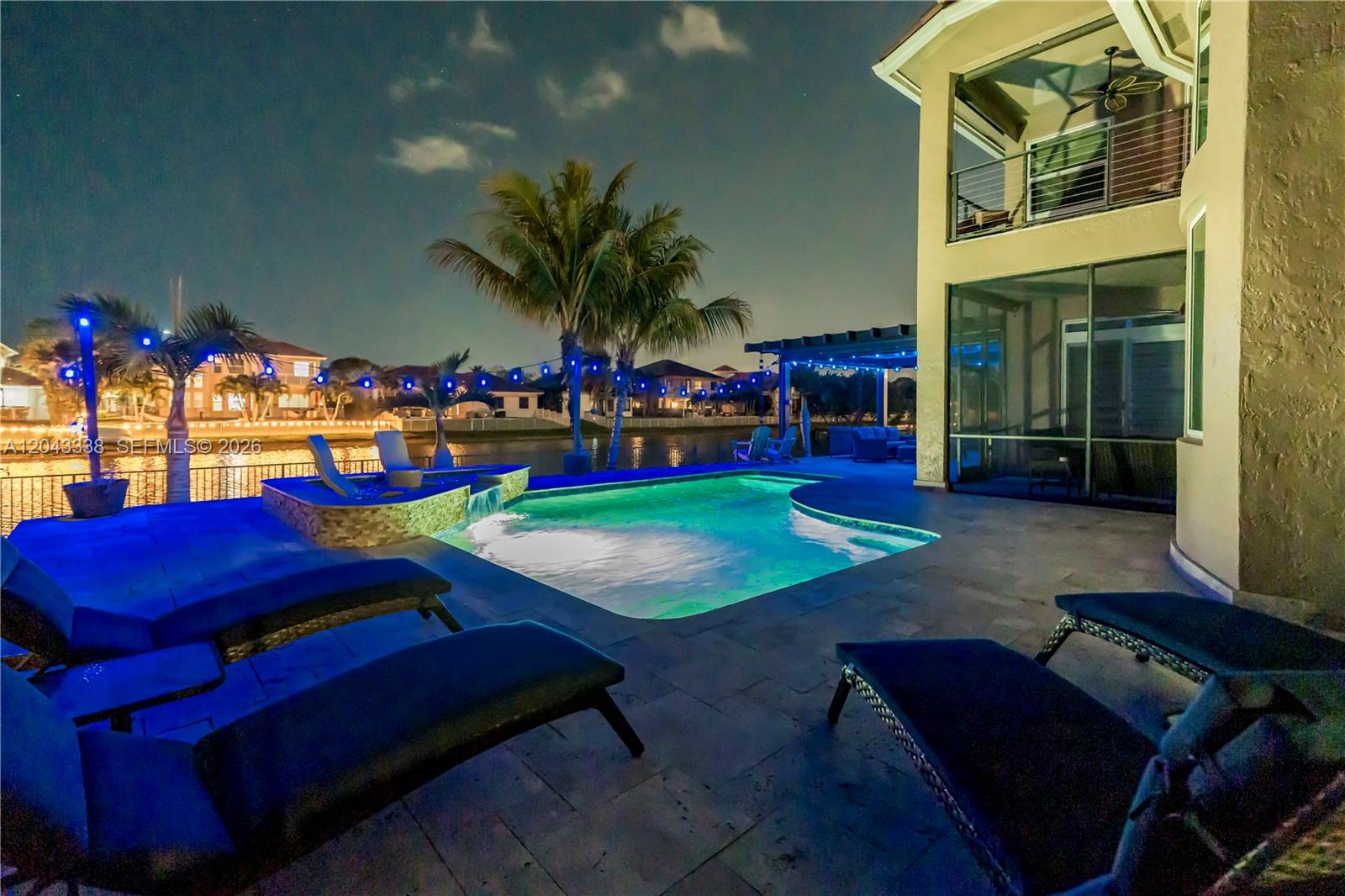 A backyard pool and patio area at night with lounge chairs and a waterfront view — 3240 SW 190th Ave, Miramar FL 33029, MIRAMAR, FL