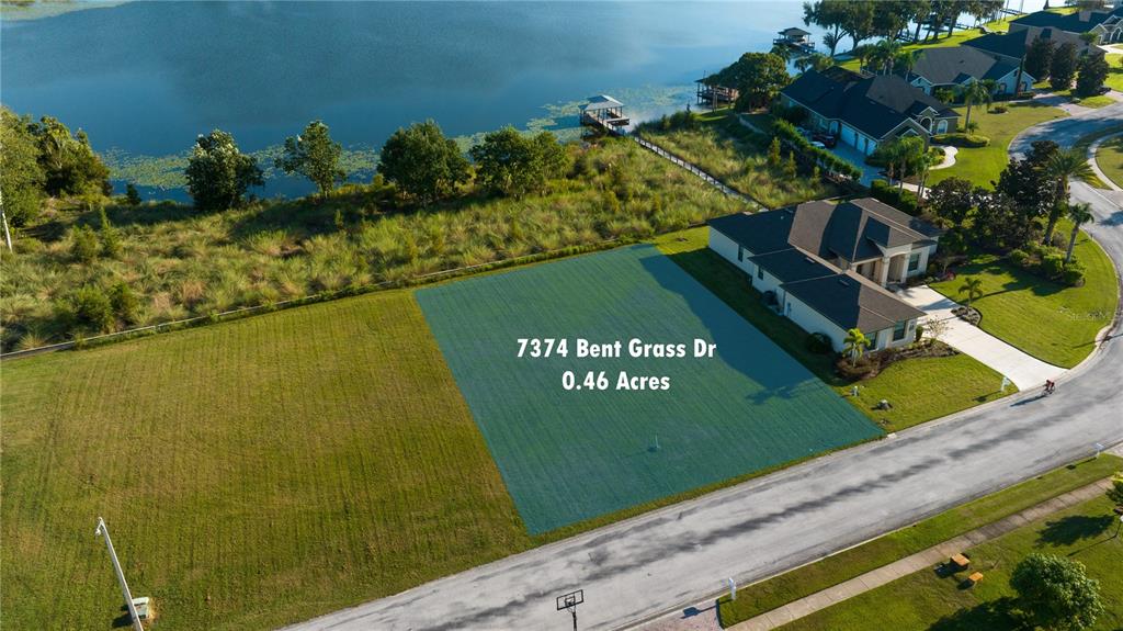 An aerial view shows a vacant, rectangular residential lot highlighted in green next to a house — 7374 BENT GRASS DRIVE, WINTER HAVEN, FL