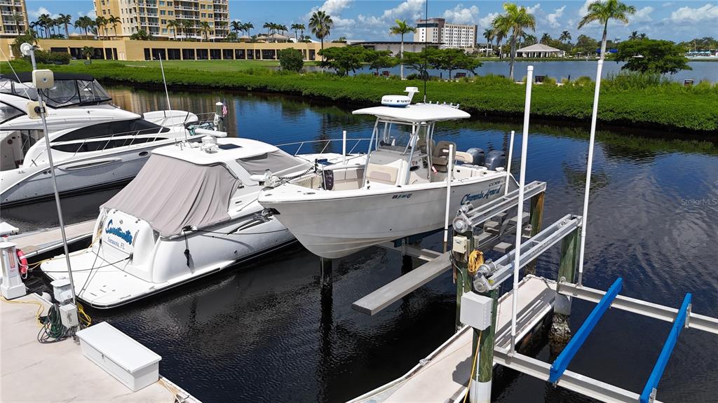 Two boats are docked at a marina with a multi-story building in the background — 102 RIVIERA DUNES WAY UNIT N-20, PALMETTO, FL