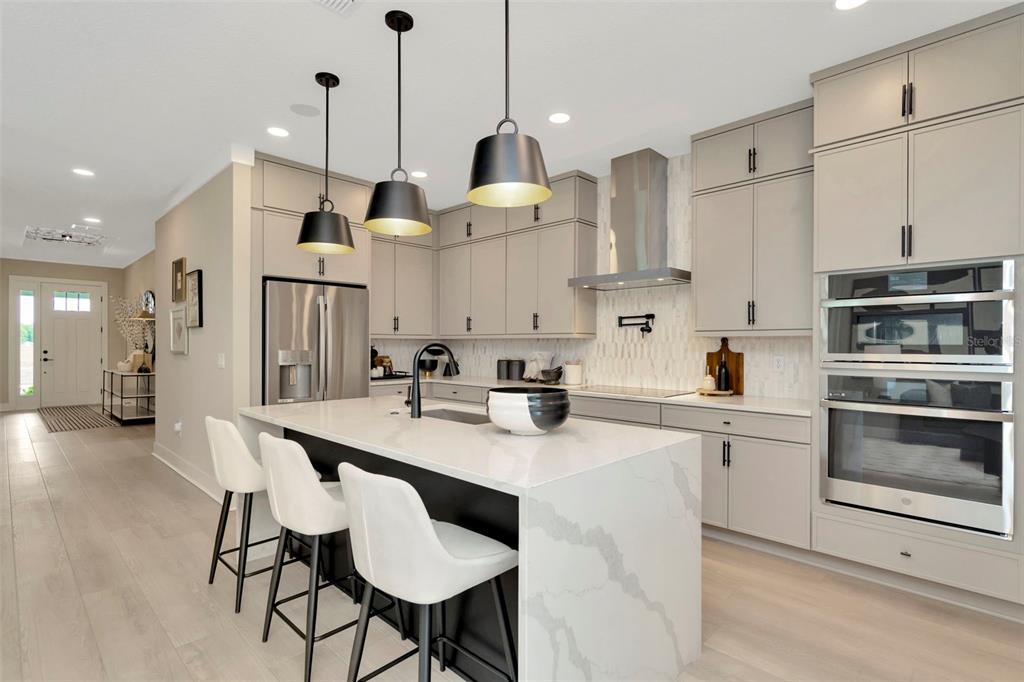A modern kitchen features light gray cabinetry, a white quartz island, and three pendant lights — 3864 ROCKY ISLAND ROAD, NEW PORT RICHEY, FL