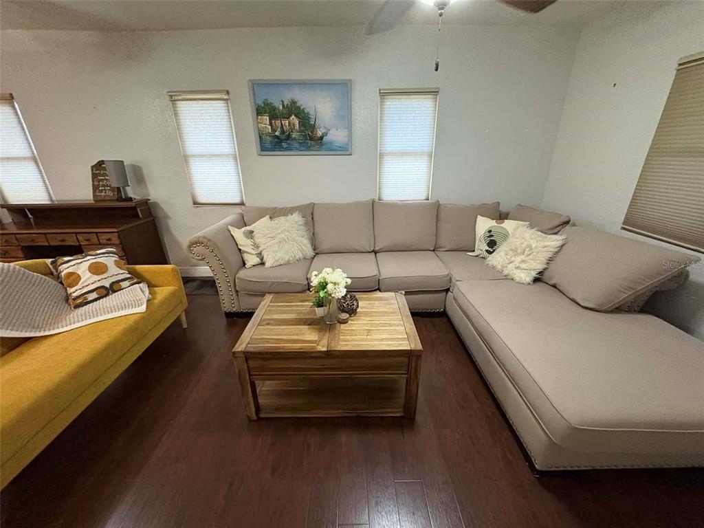A living room features a large beige sectional sofa, a yellow chair, and a wooden coffee table — 1040 S OHIO AVE, LAKELAND, FL