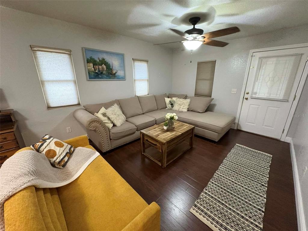 A living room features a yellow sofa, a sectional, a wooden desk, and dark flooring — 1040 S OHIO AVE, LAKELAND, FL