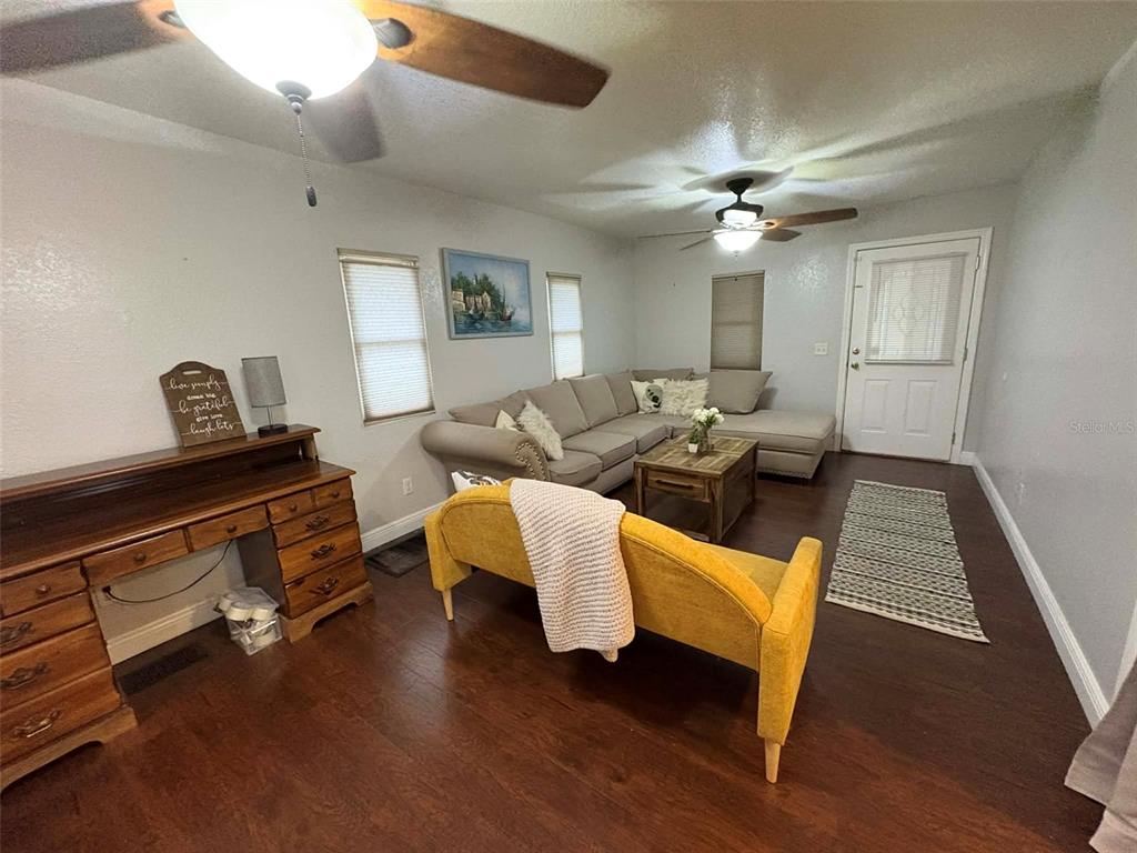 A room features a wooden desk, a tall bookshelf, two windows, and dark flooring — 1040 S OHIO AVE, LAKELAND, FL