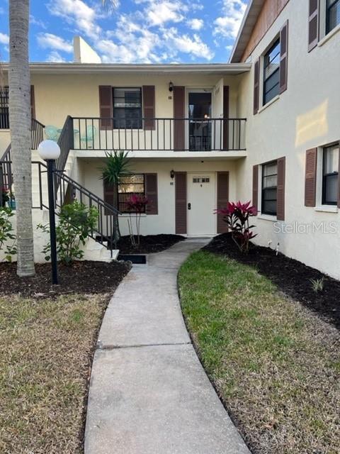 A two-story apartment building exterior features a concrete walkway leading to a central entrance — 5400 34TH STREET W UNIT E8, BRADENTON, FL