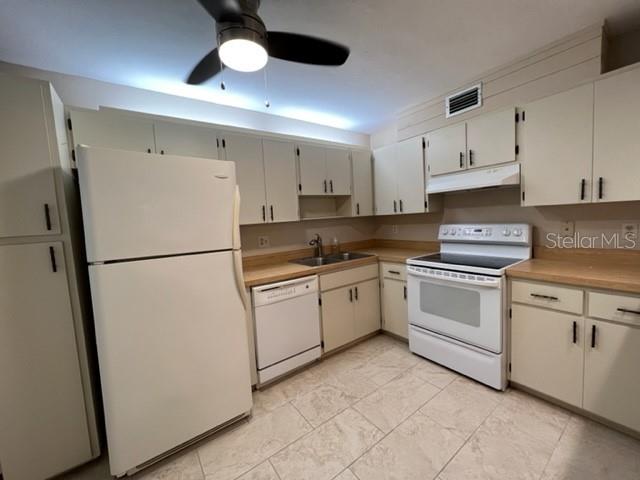A kitchen features white cabinets, a white refrigerator, a dishwasher, and a white stove — 5400 34TH STREET W UNIT E8, BRADENTON, FL