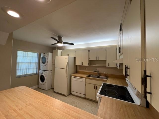 A kitchen with light-colored cabinets, white appliances, a stacked washer-dryer, and a wood-topped counter — 5400 34TH STREET W UNIT E8, BRADENTON, FL