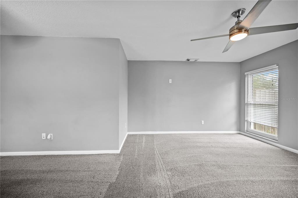 An empty bedroom features gray walls, gray carpeting, a ceiling fan, and a window — 2015 RONALD CIRCLE, SEFFNER, FL
