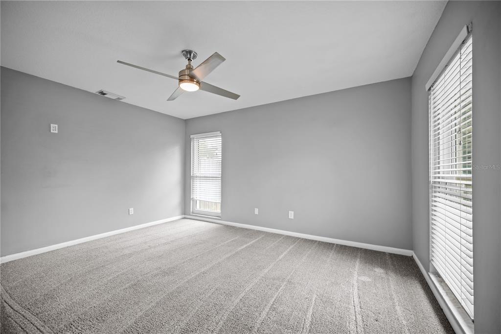 An empty bedroom with gray walls, gray carpet, a ceiling fan, and two windows — 2015 RONALD CIRCLE, SEFFNER, FL