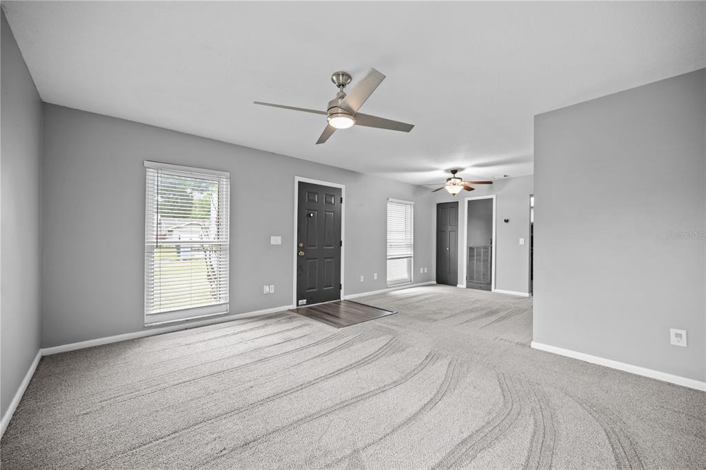 A living room with gray walls, carpeted flooring, a ceiling fan, and a black front door — 2015 RONALD CIRCLE, SEFFNER, FL