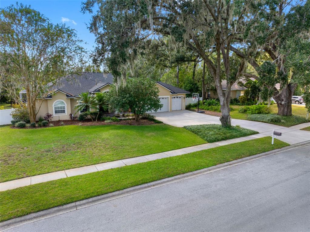 A single-story house with a two-car garage, a green lawn, and large oak trees — 121 MYRTLE RIDGE ROAD, LUTZ, FL