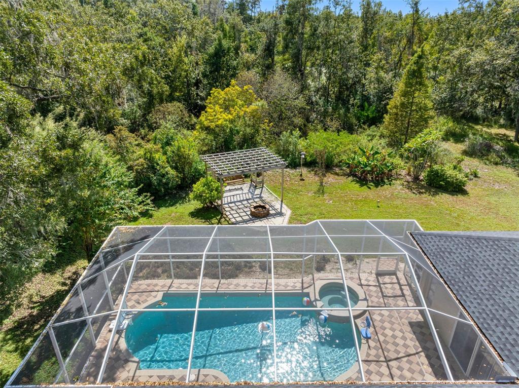 An elevated view of a screened-in pool and spa with a nearby wooden pergola — 121 MYRTLE RIDGE ROAD, LUTZ, FL