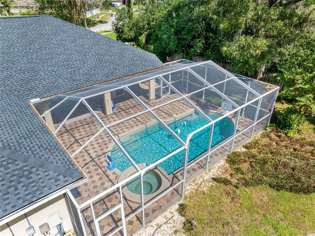 An aerial view of a backyard swimming pool and spa enclosed by a screened lanai — 121 MYRTLE RIDGE ROAD, LUTZ, FL