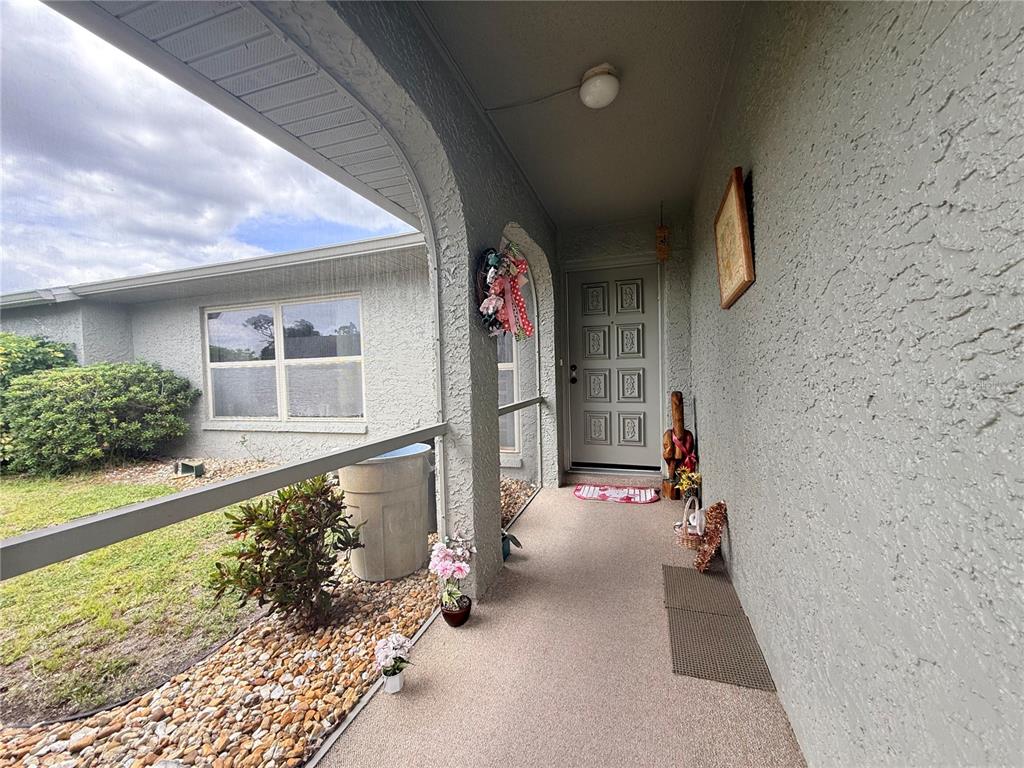 A covered concrete porch leads to a gray front door with eight rectangular panels — 22506 GLEN AVENUE, PUNTA GORDA, FL
