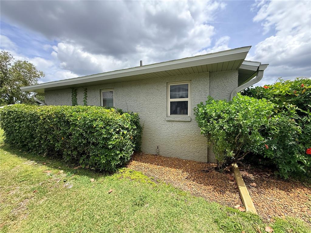 The exterior of a stucco house features a window, a hedge, and a gravel bed — 22506 GLEN AVENUE, PUNTA GORDA, FL