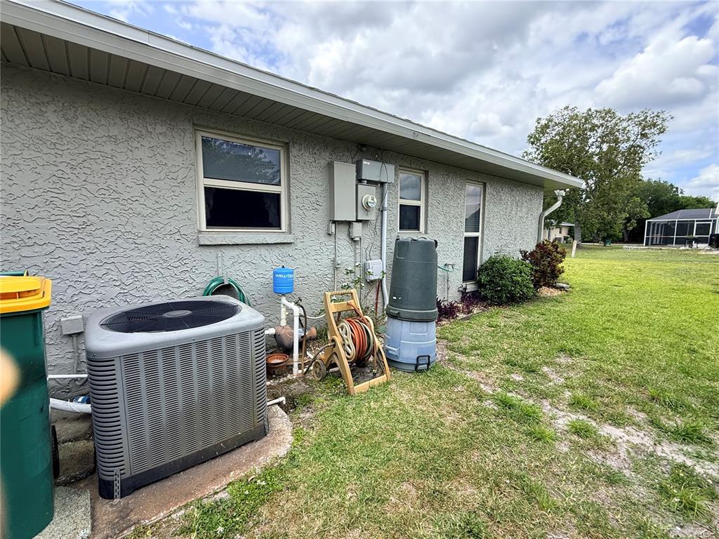 The exterior of a house features an HVAC unit, a well tank, and a hose reel — 22506 GLEN AVENUE, PUNTA GORDA, FL