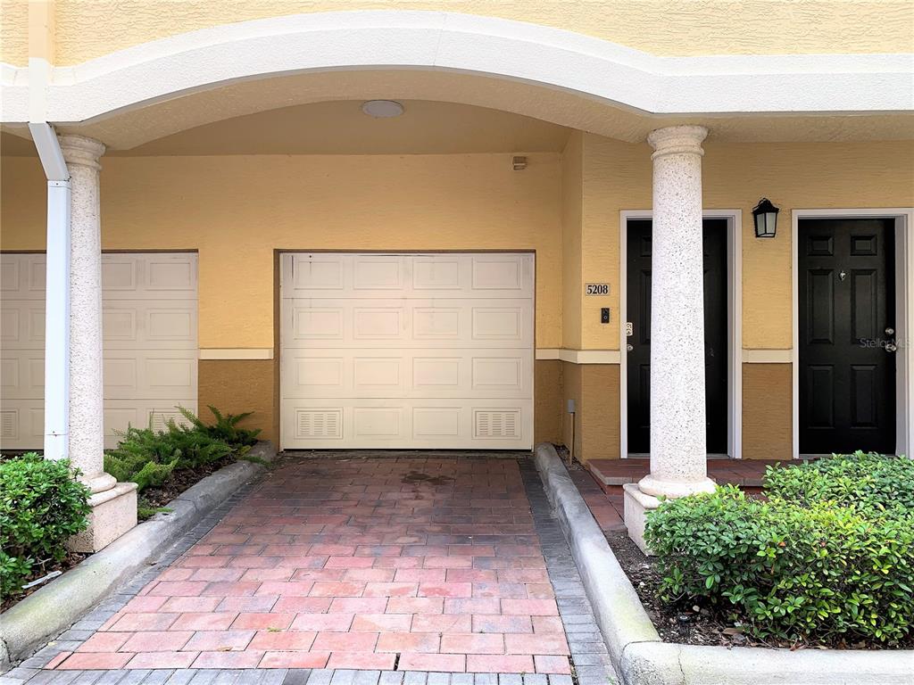 A paved driveway leads to a garage door and a black front door under an archway — 5208 HAMPTON BEACH PLACE UNIT 5208, TAMPA, FL