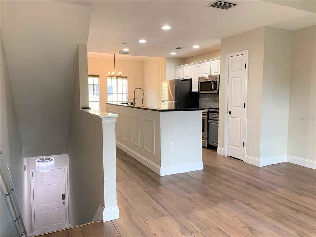 An interior view shows a kitchen with dark countertops, white cabinets, and wood-look flooring — 5208 HAMPTON BEACH PLACE UNIT 5208, TAMPA, FL