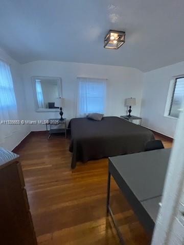 A bedroom features a bed, two nightstands, a mirror, and hardwood floors under a ceiling light — 2811 Indian Creek Dr, Miami Beach FL 33140, MIAMI BEACH, FL