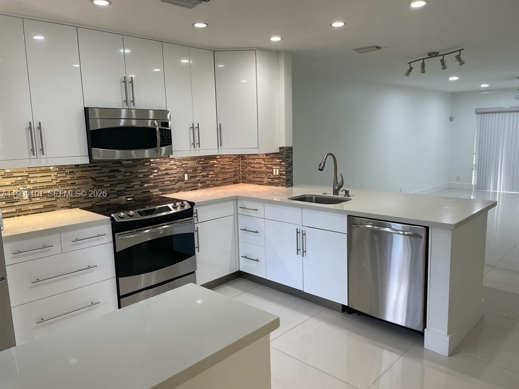 A modern kitchen features white cabinets, stainless steel appliances, and a tiled backsplash — 454 Lakeview Dr # 2, Weston FL 33326, WESTON, FL