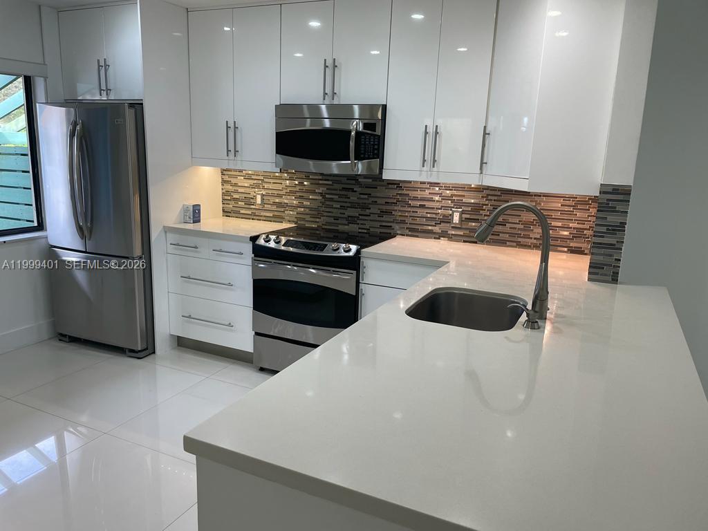 A modern kitchen features white cabinets, stainless steel appliances, and a white quartz countertop — 454 Lakeview Dr # 2, Weston FL 33326, WESTON, FL
