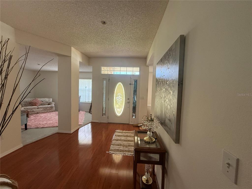 An entryway with hardwood floors, a front door with a decorative oval window, and artwork — 4 BALLARD LANE, PALM COAST, FL