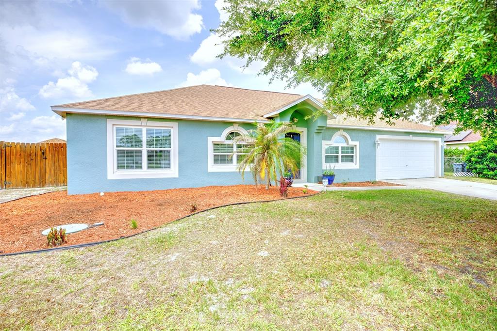A single-story light blue house with a tan roof, a garage, and a landscaped yard — 4710 TARREGA STREET, SEBRING, FL