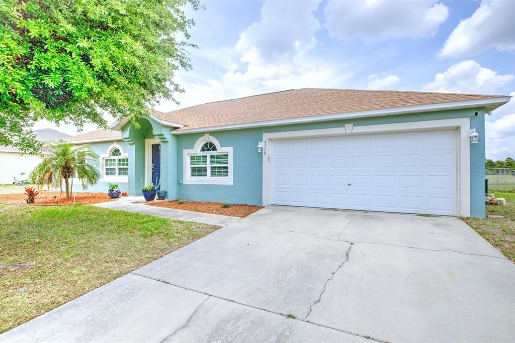 A teal single-story house with a white garage door and a concrete driveway — 4710 TARREGA STREET, SEBRING, FL