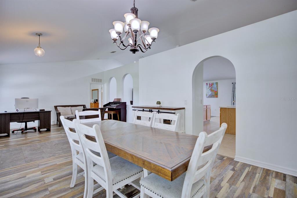 A dining room features a wooden table, white chairs, a chandelier, and arched doorways — 4710 TARREGA STREET, SEBRING, FL