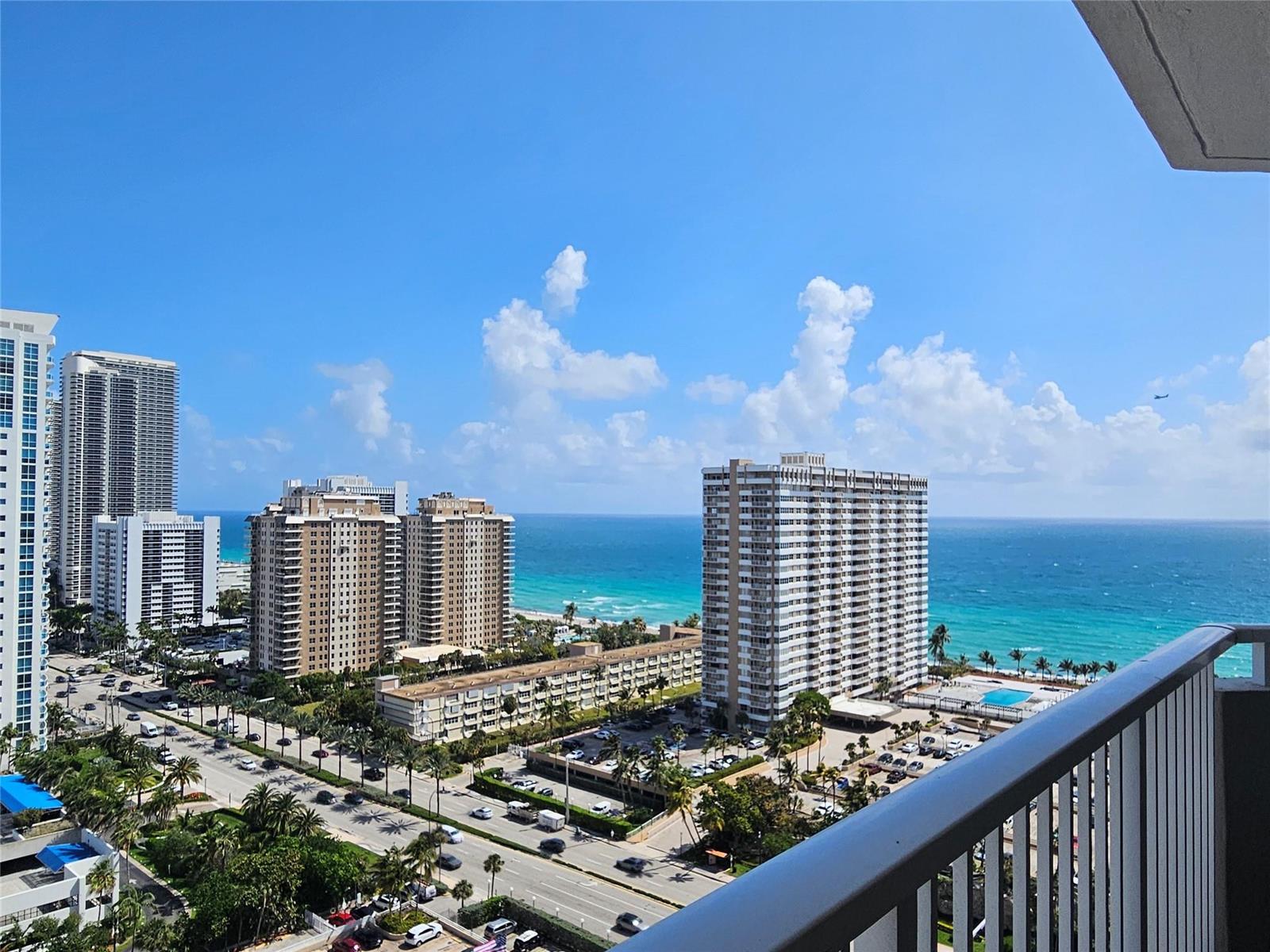 A high-angle view from a balcony overlooking coastal high-rise buildings, a road, and the ocean — 1985 S Ocean Drive # 20d, Hallandale Beach FL 33009, HALLANDALE BEACH, FL