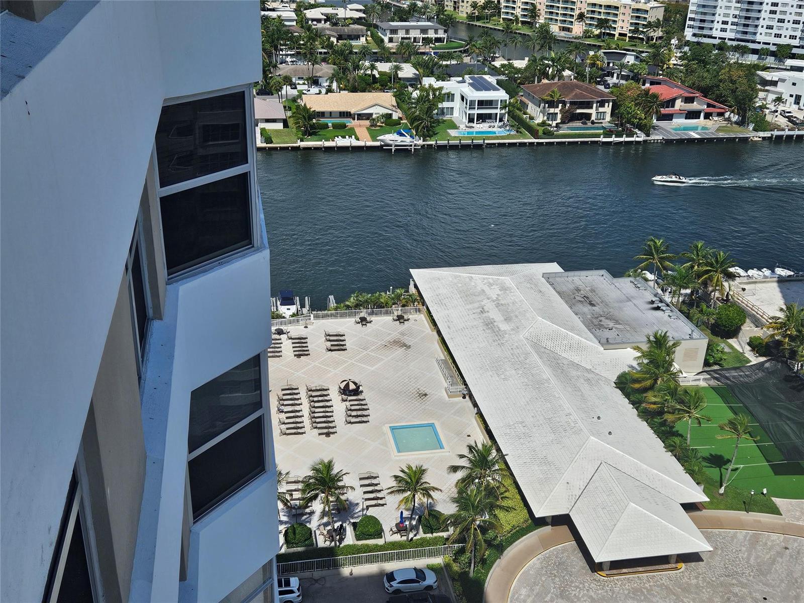 An elevated view shows a building exterior, a pool deck with lounge chairs, and a canal — 1985 S Ocean Drive # 20d, Hallandale Beach FL 33009, HALLANDALE BEACH, FL