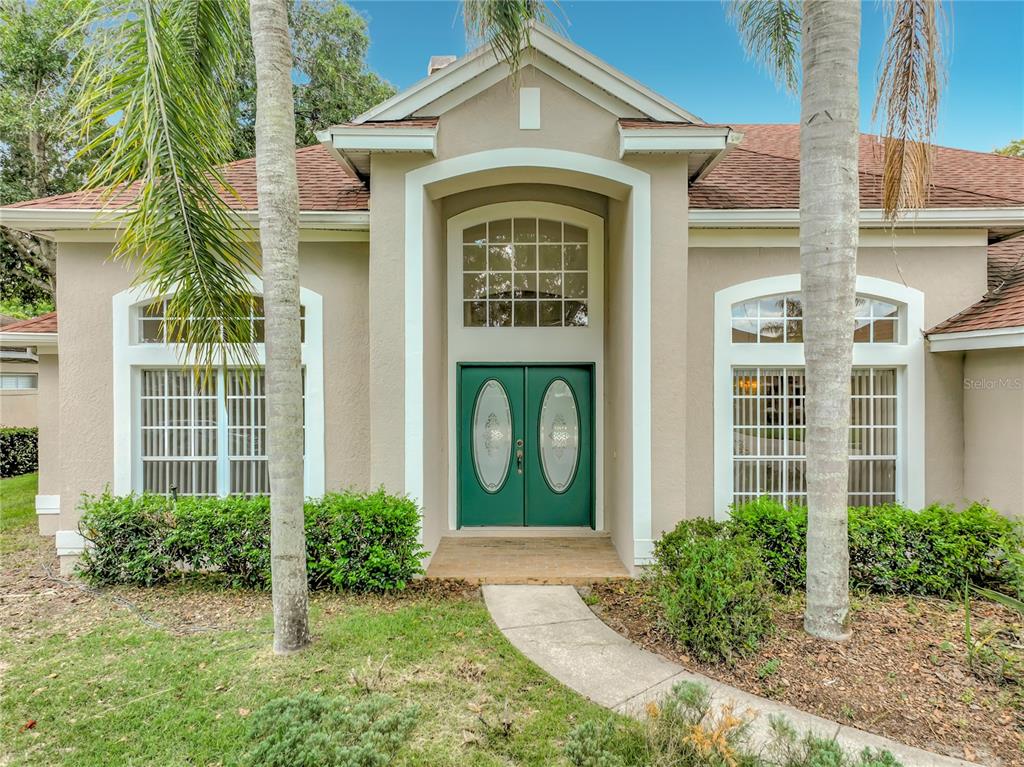 A tan house exterior features a green double front door and a large arched window — 635 LONG LAKE DRIVE, OVIEDO, FL
