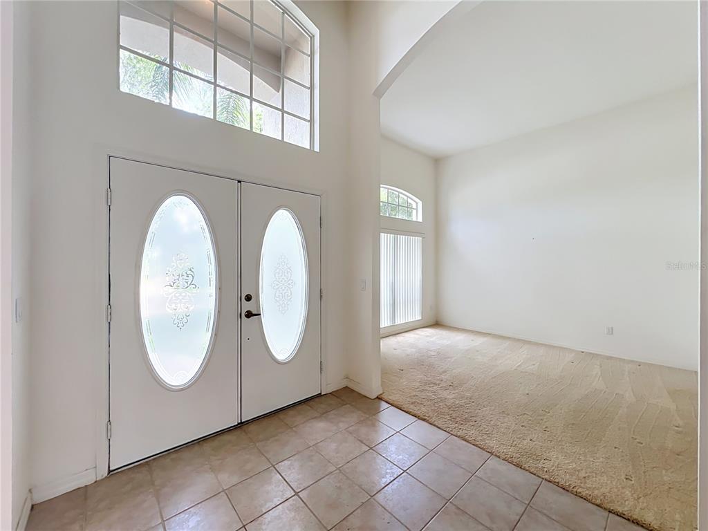 An entryway with tiled floors and double doors leads to a carpeted room with windows — 635 LONG LAKE DRIVE, OVIEDO, FL
