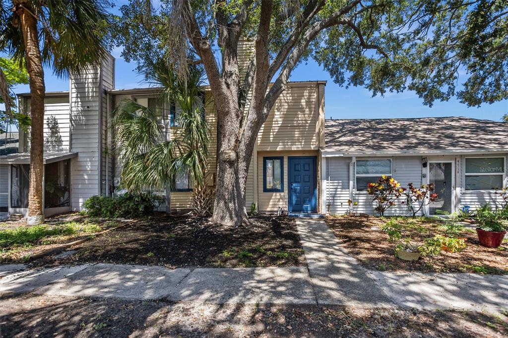 A two-story townhouse with light siding, a blue front door, and a large shade tree — 4712 STONEPOINTE PLACE, TAMPA, FL