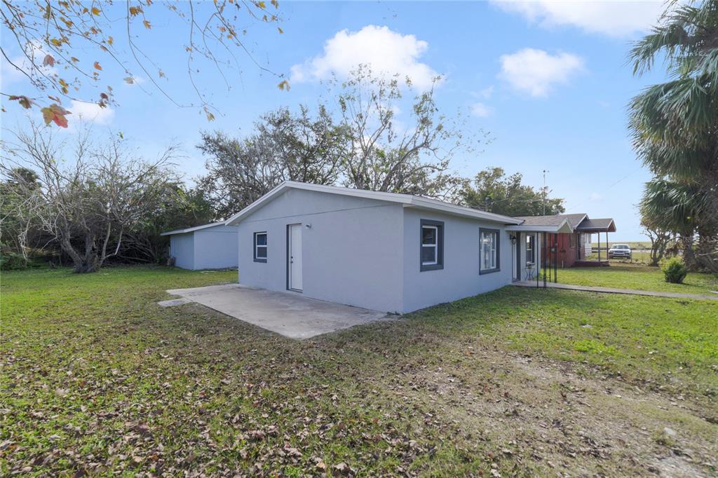 A gray single-story house with a concrete patio and a grassy yard under a blue sky — 2441 CHURCH STREET, SANFORD, FL