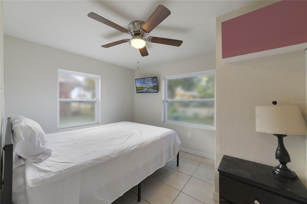 A bedroom features a bed, ceiling fan, two windows, and a lamp on a dresser — 2441 CHURCH STREET, SANFORD, FL