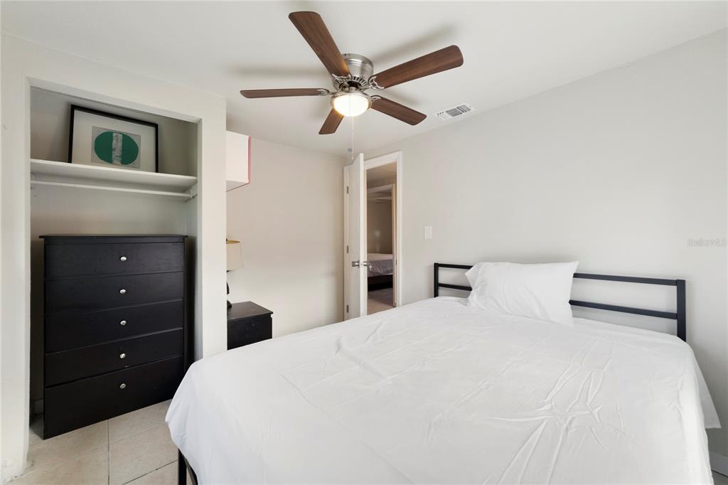 A bedroom features a white bed, a black dresser in a closet, and a ceiling fan — 2441 CHURCH STREET, SANFORD, FL