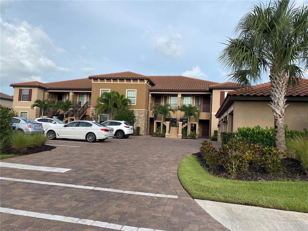 A two-story apartment building with a paved parking lot and palm trees in front — 12730 SORRENTO WAY UNIT 103, BRADENTON, FL