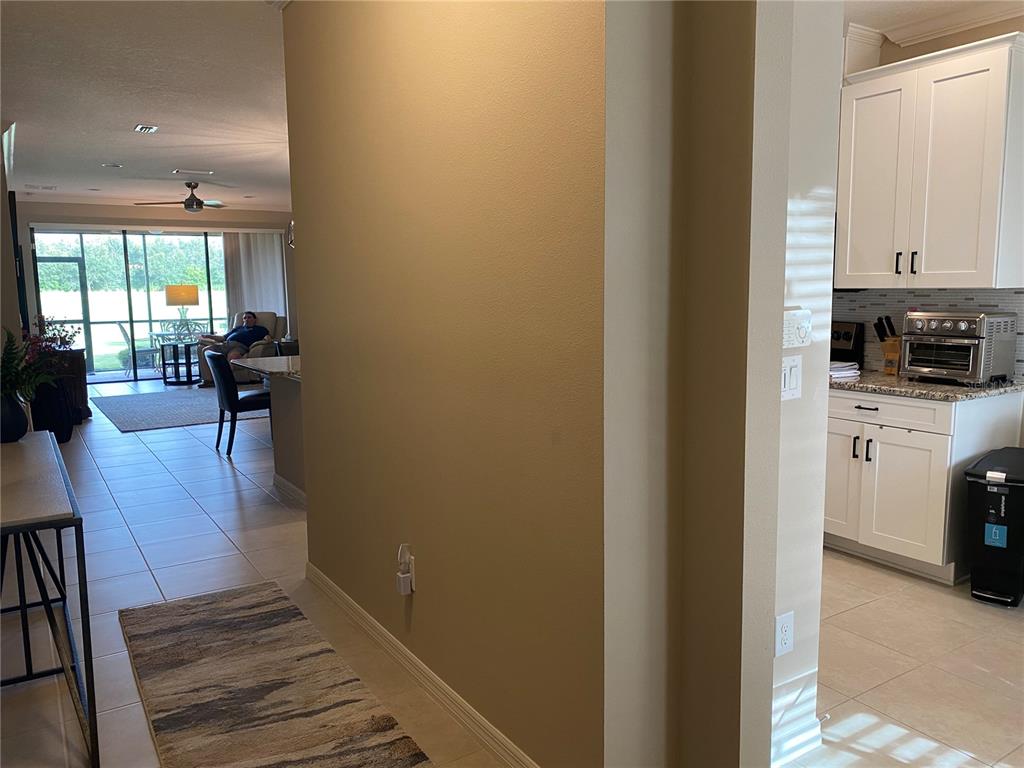 A view from a hallway looking toward a kitchen and a living area with a lanai — 12730 SORRENTO WAY UNIT 103, BRADENTON, FL