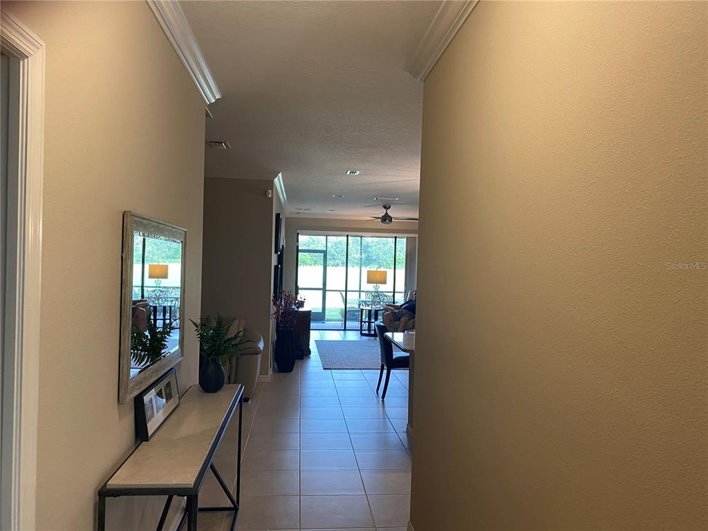 A hallway with tile flooring leads to an open living area with a screened patio — 12730 SORRENTO WAY UNIT 103, BRADENTON, FL