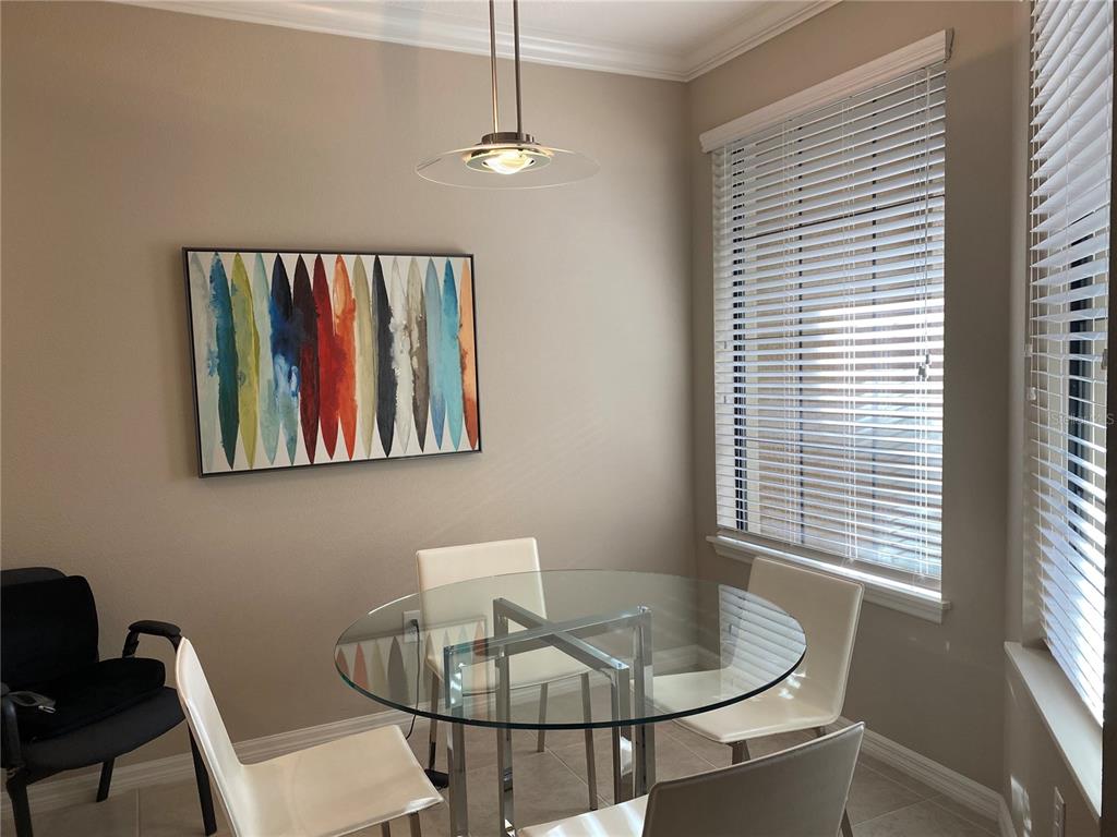 A dining area features a glass-topped table, four white chairs, and abstract wall art — 12730 SORRENTO WAY UNIT 103, BRADENTON, FL