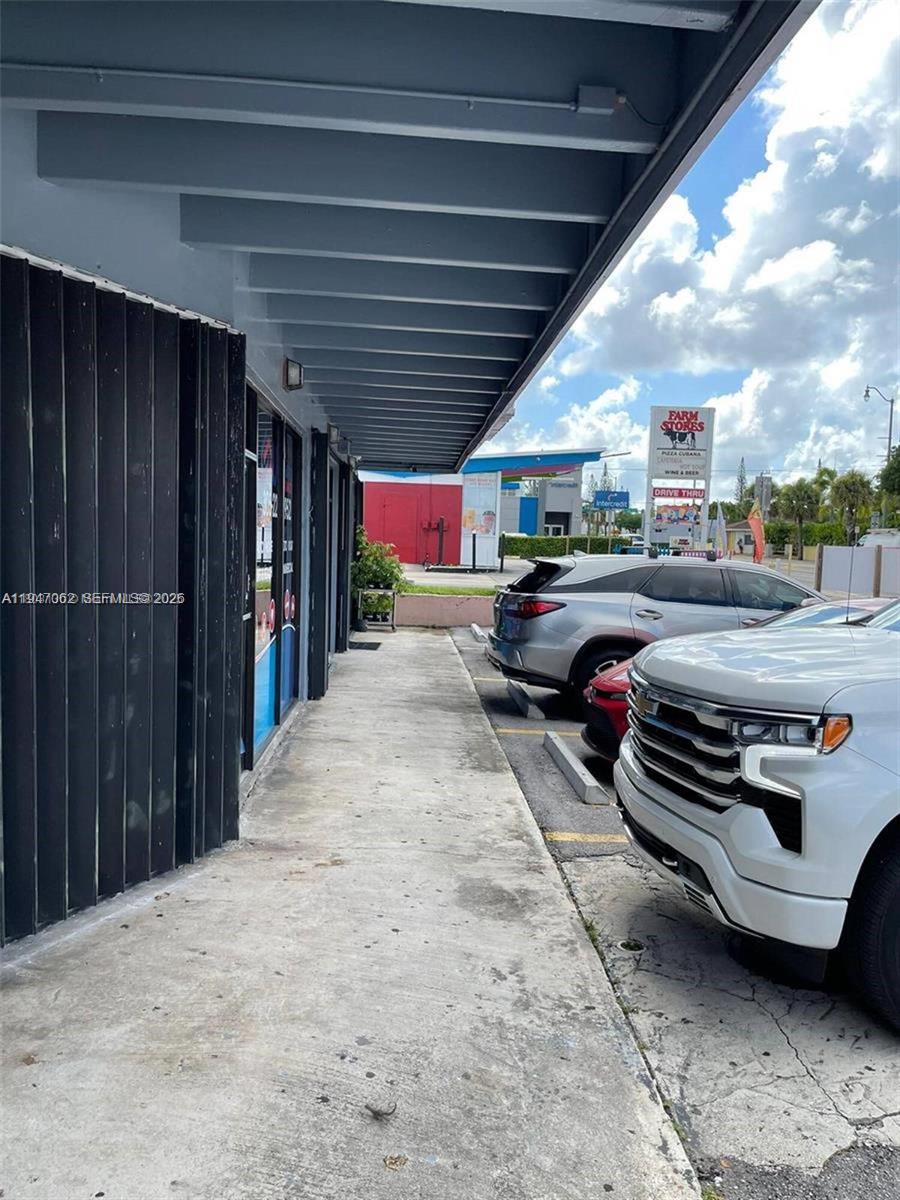A concrete sidewalk runs along the exterior of a commercial building next to parked cars — 4757 SW 8th St # 4747, Miami FL 33134, MIAMI, FL