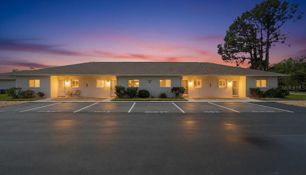 The exterior of a single-story residential building features a walkway, gravel landscaping, and a doorway — 12538 SW KINGSWAY CIRCLE UNIT 1503, LAKE SUZY, FL