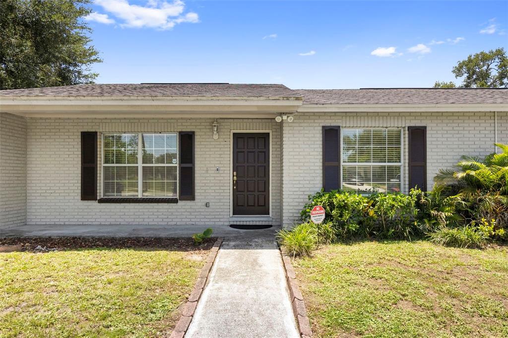 A single-story house with a white brick exterior, dark shutters, and a central front door — 8904 W FLORA STREET, TAMPA, FL