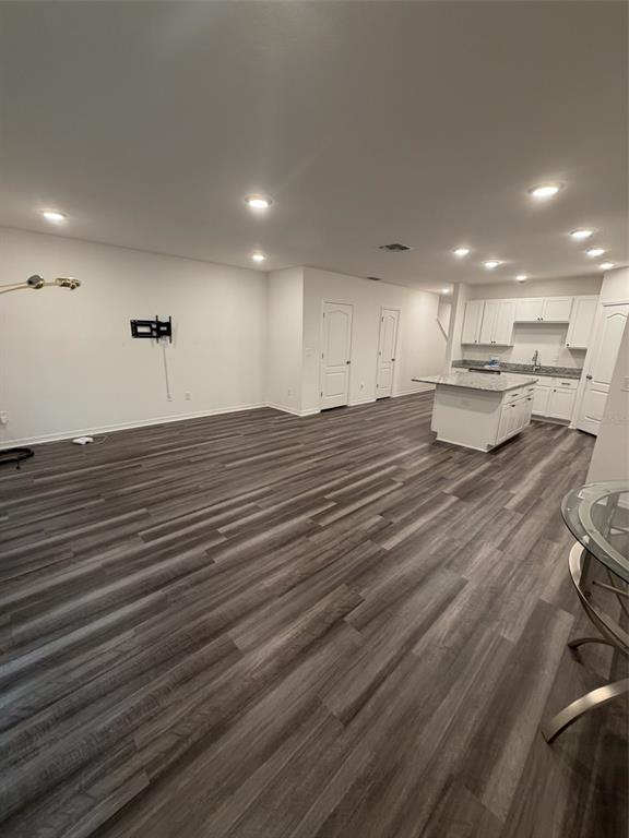 An open-concept living area features wood-look flooring, recessed lighting, and a kitchen with white cabinetry — 4743 DEER TRACK STREET, TAMPA, FL